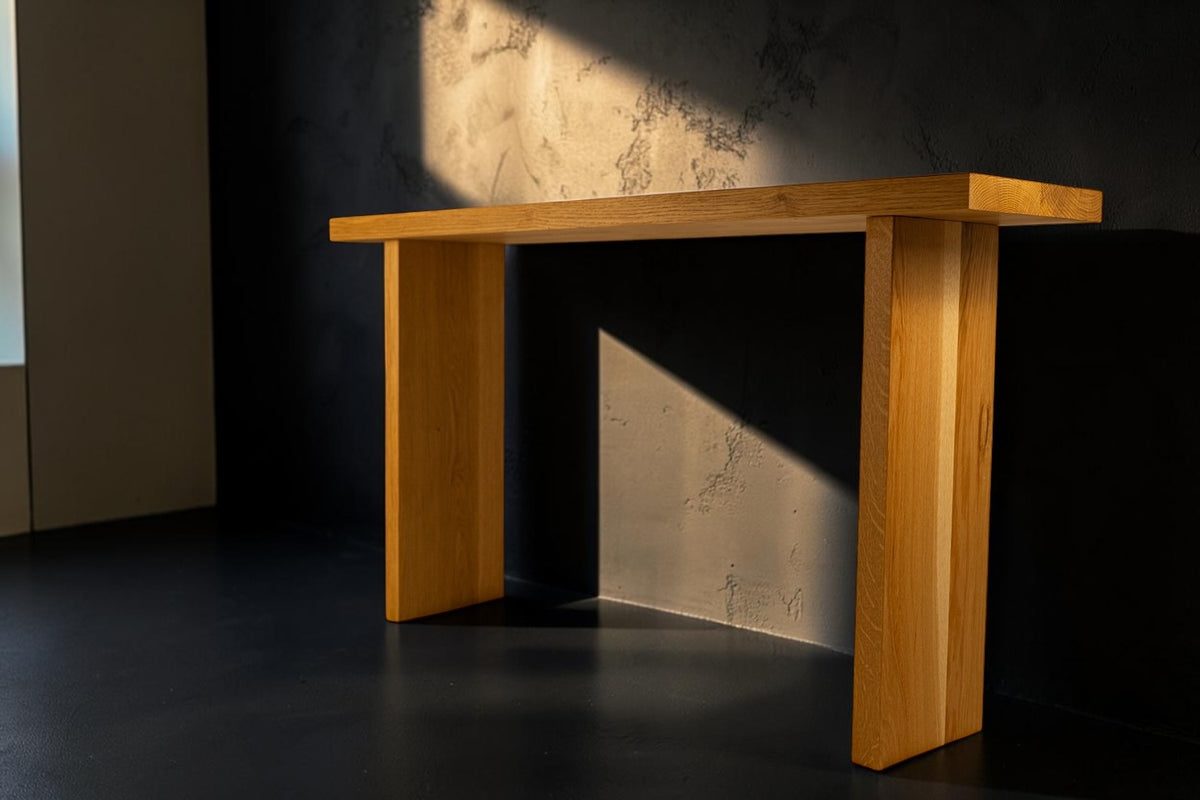 Minimal solid oak console table on a dark studio background