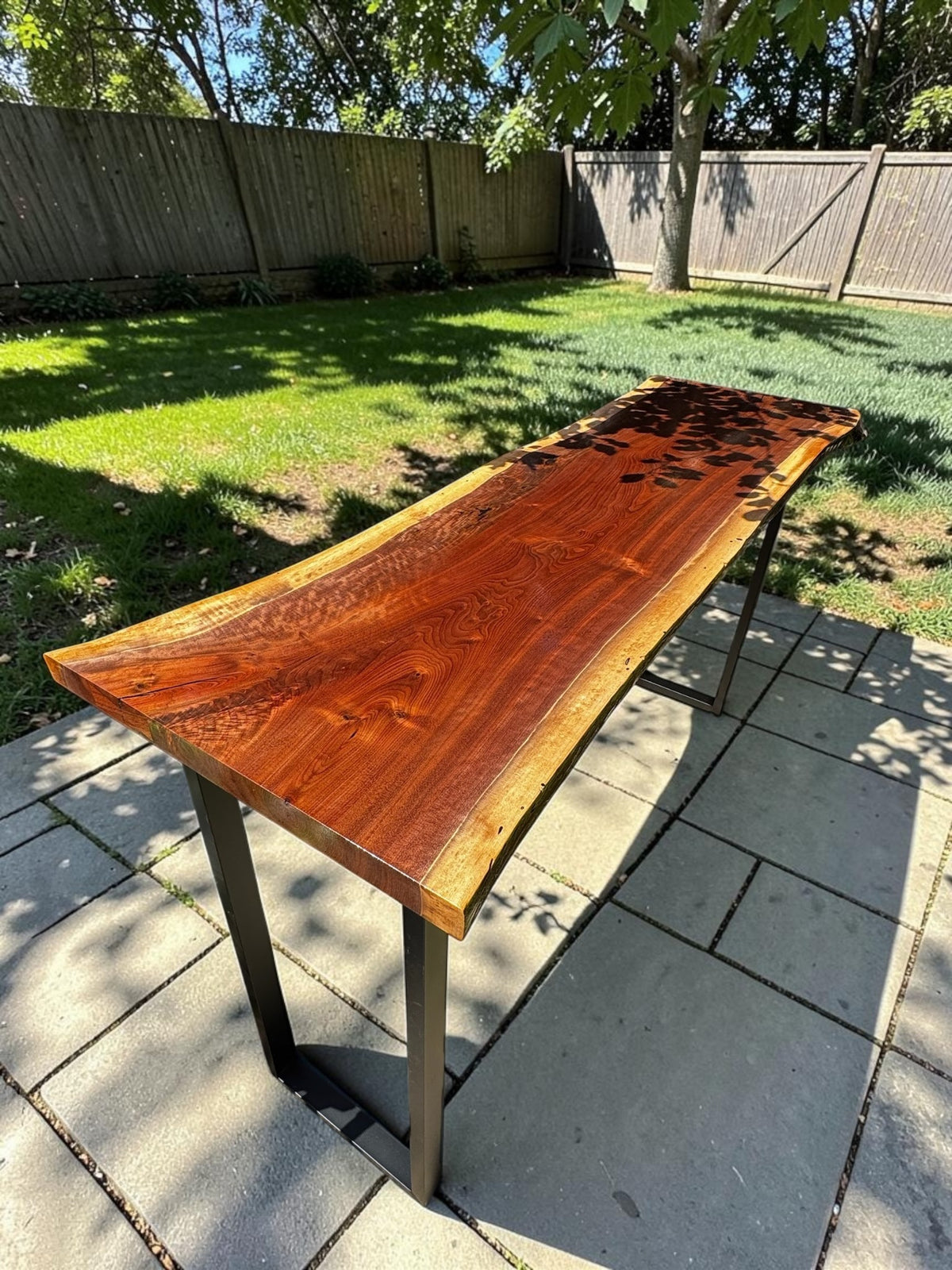Live edge solid wood table photographed outdoors on a stone patio