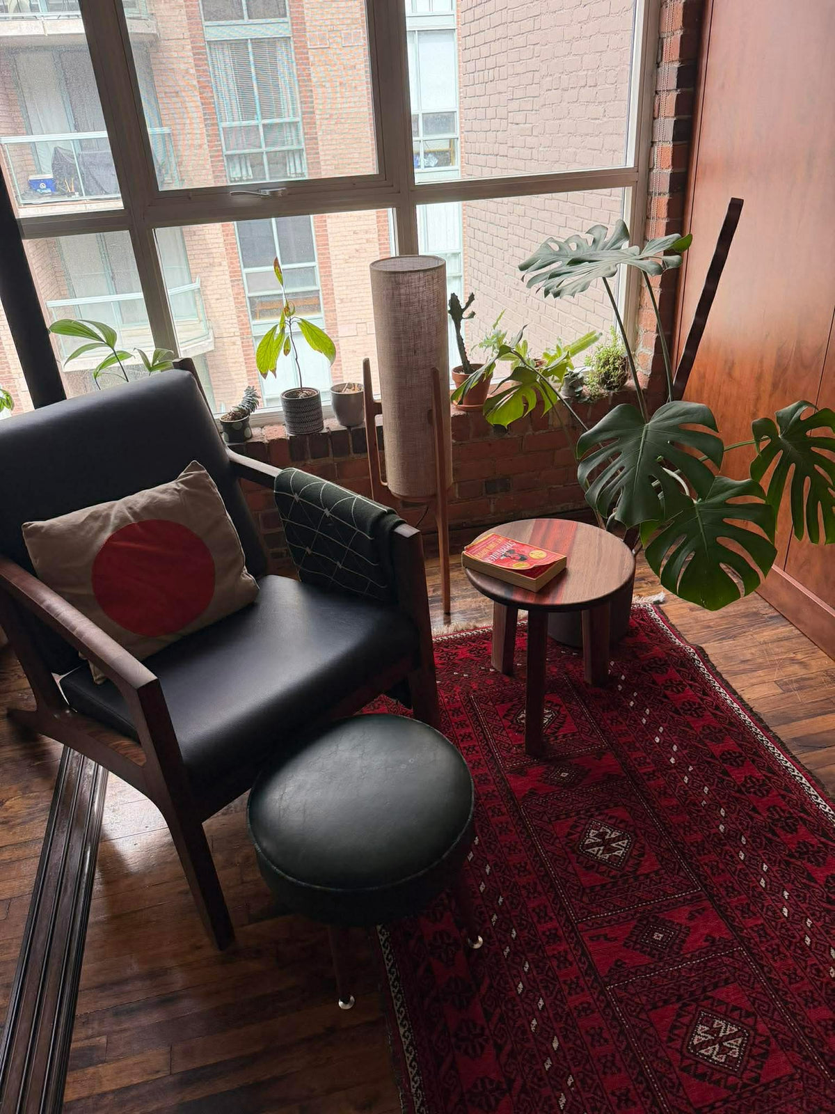 Small round solid wood side table in a bright plant-filled apartment