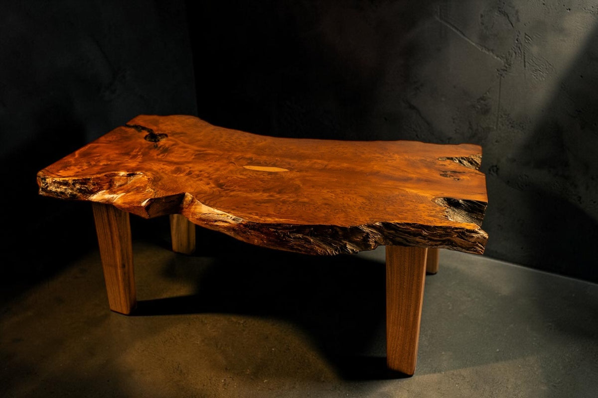 Sculptural live edge solid wood coffee table on a dark studio background