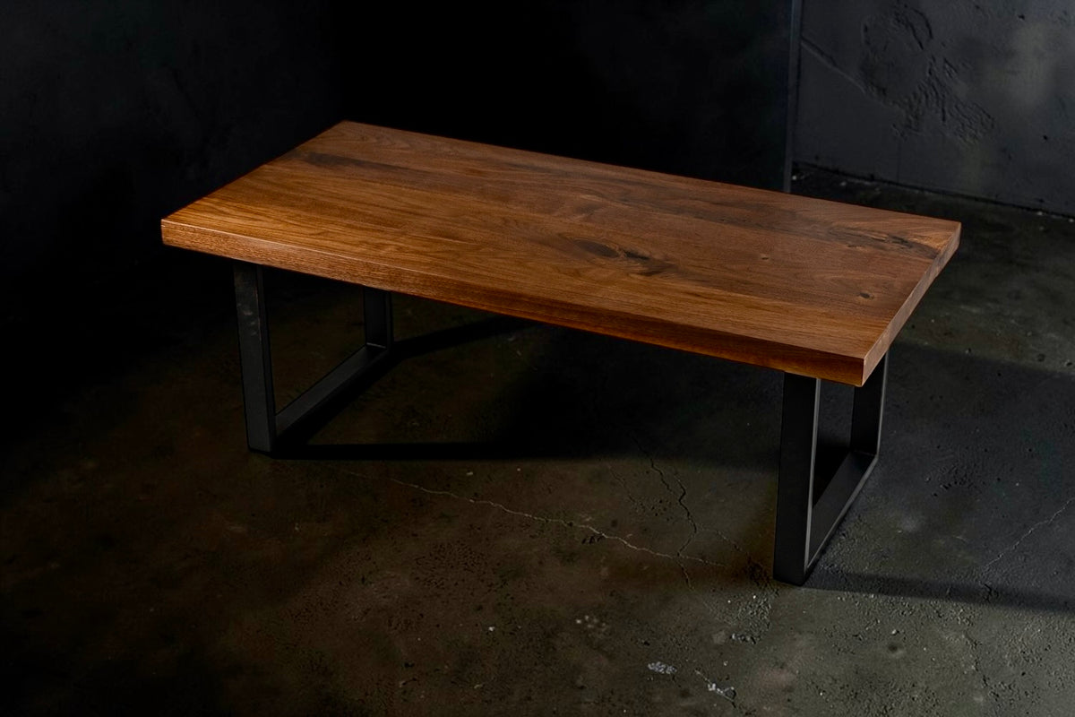 Walnut coffee table with black steel legs on a dark studio background