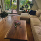 Walnut live edge coffee table beside a sectional in a bright customer home